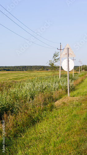 plain with green grass electric poles and road sign at summer. background. nature.