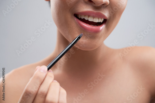 Cheerful woman applying lipstick