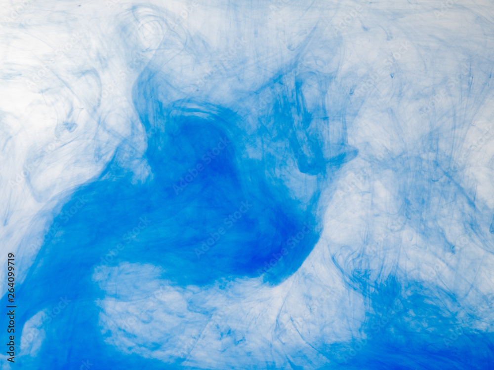 Droplet of blue paint mixing with water, close up view. Blurred background. Acrylic clouds in liquid, abstract background. Blue abstract pattern of acrylic paint in water. Ink in liquid