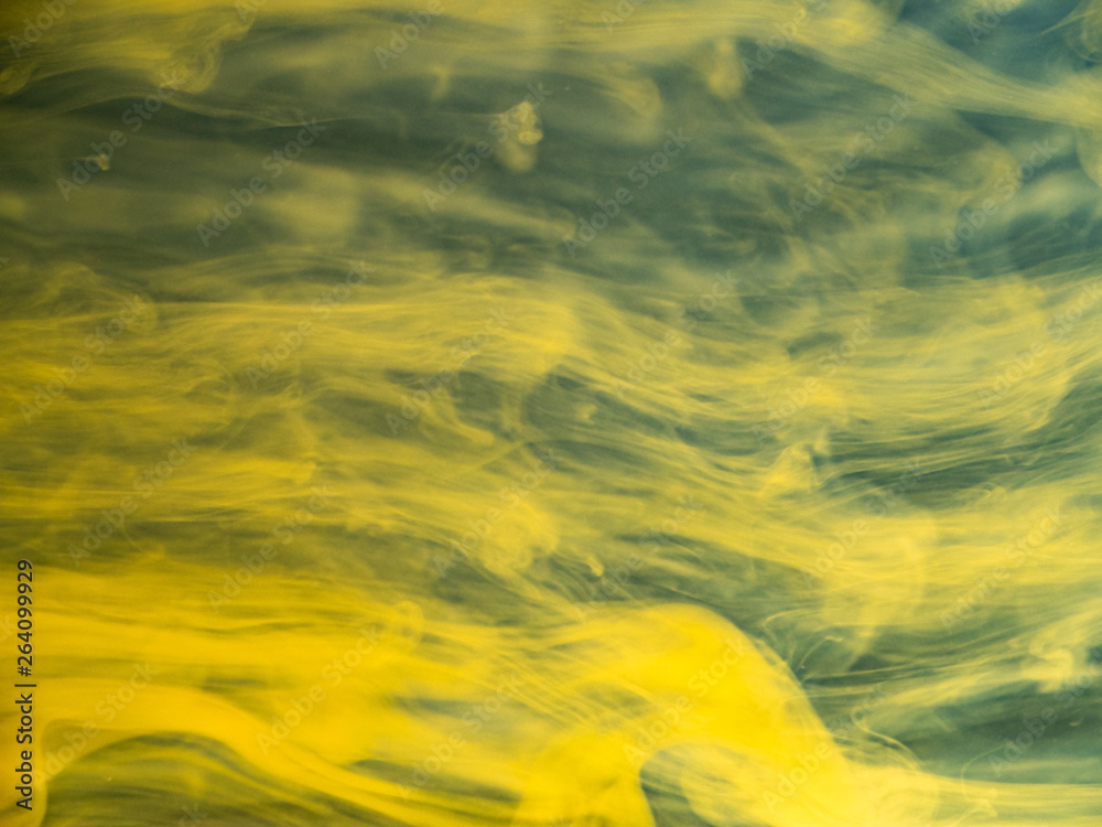 Fototapeta Abstract flows of yellow paint in water, close up view. Blurred background. Droplet of acrylic ink dissolving into water, abstract pattern. Ink mixing with liquid, abstract background
