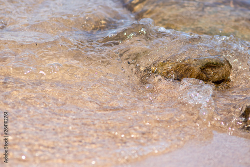 Klares Wasser fließt am Strand über Steine und Felsen