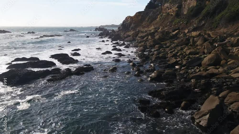Aerial views of a rocky California Coastline with crashing, deep-blue waves on a cool dreary day