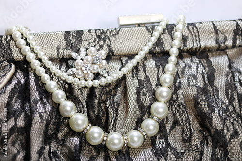 真珠のアクセサリー(ネックレスとブローチ)とレース素材のハンドバッグ
