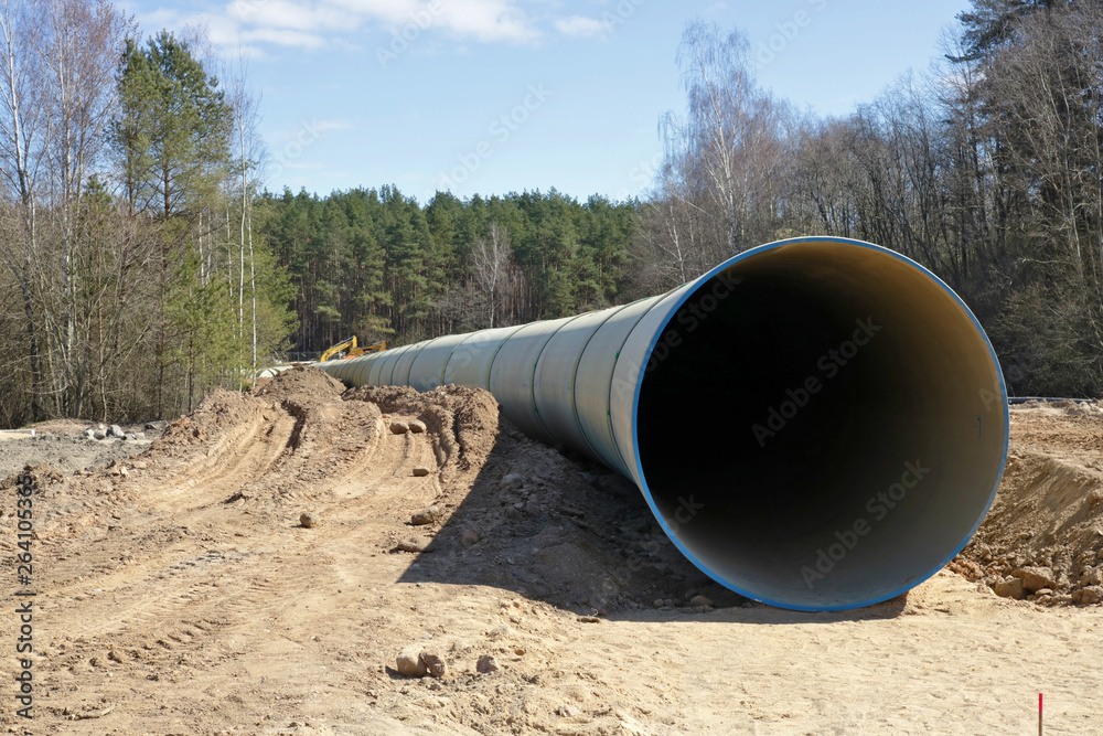 Large  concrete sewer pipe lie on  construction site in the spring forest.