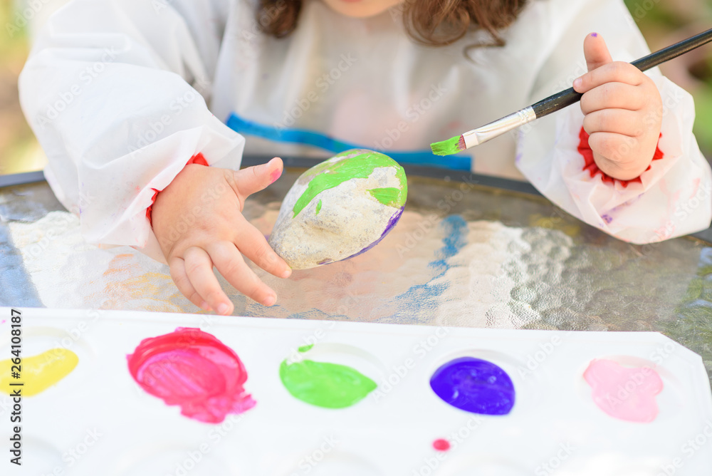 Close-up child hands painting by paintbrush and watercolors. Kids hand with brushes drawing on a stone. Close-up child hands painting by paintbrush and watercolors. Kids hand with brushes drawing on a stone.