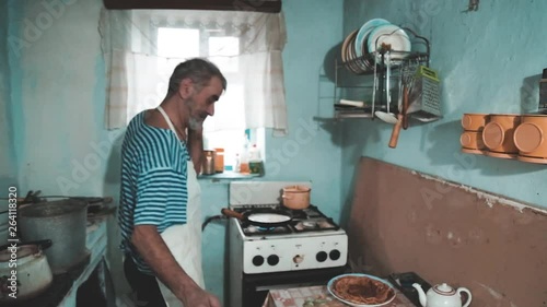 Happy smiling older man throwing a pancake in a pan in my old kitchen. Positive emotions, facial expressions, kitchen game