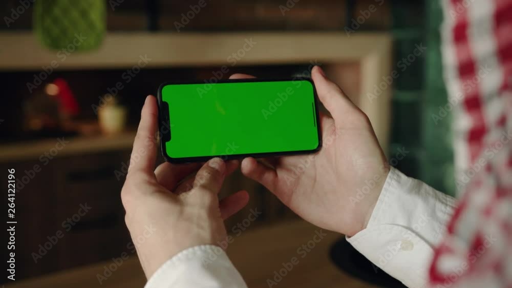 Hands hold use smartphone with horizontal green screen on kitchen at home cup breakfast apple fruit browse house shopping internet money finger payment communication close up slow motion