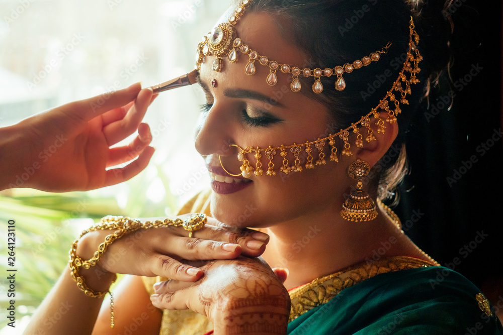 portrait indian beautiful female in golden rich jewelery tradition saree  face closeup professional make-up wearing bindi on head ,with bindis maang  tikka ,nath,nose Pin.morning of the bride visagiste Stock Photo | Adobe