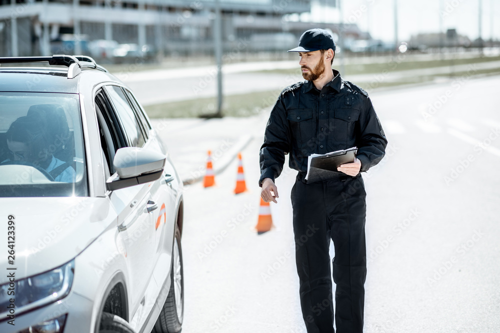Fototapeta premium Policeman walking to the stopped car for the violation traffic rules on the city road