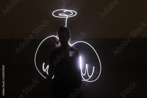 Obraz na plátně woman in the image of an angel with painted light wings on a black background