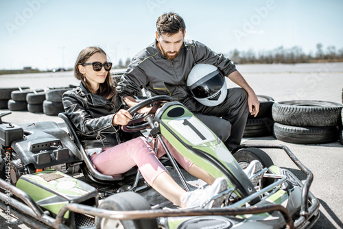 Man in sportswear instructing young woman driver before racing on the go-karts on the track outdoors © rh2010