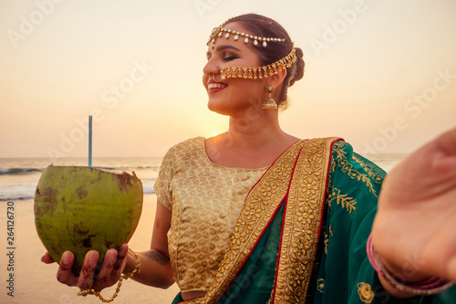 Canvas Print beautiful woman indian green fashion sari, bindis drinking coco nut water