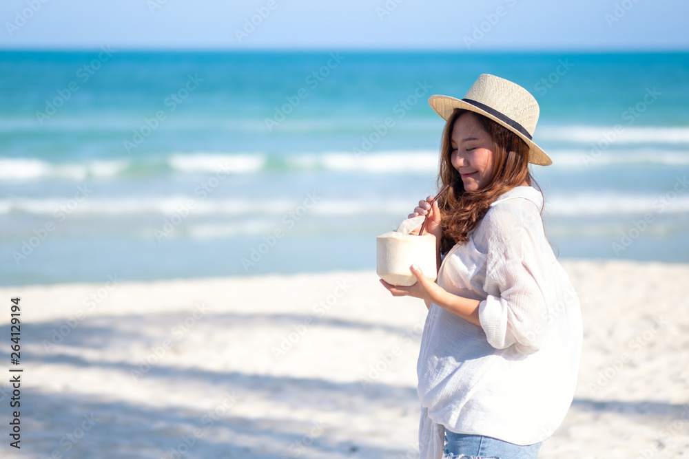 Portrait image of a beautiful asian woman holding and drinking coconut juice on the beach