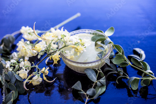 Ayurvedic herb Drumstick flowers along with some leaves on wooden surface along with its paste in a glass bowl. photo