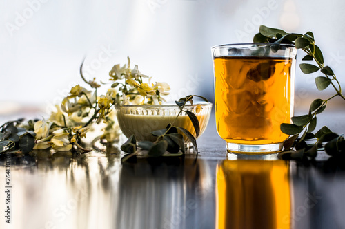 Bunch of flowers of drumstick on wooden surface along with its extracted water or tincture in a glass. photo