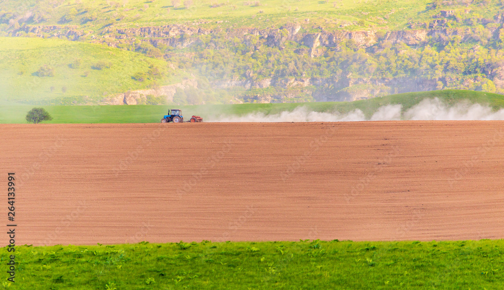 Dust from a tractor working in a field in spring - obrazy, fototapety, plakaty 