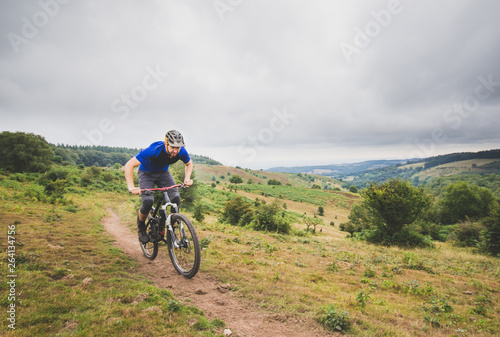 Mountain biker pushing hard up climb in English hills