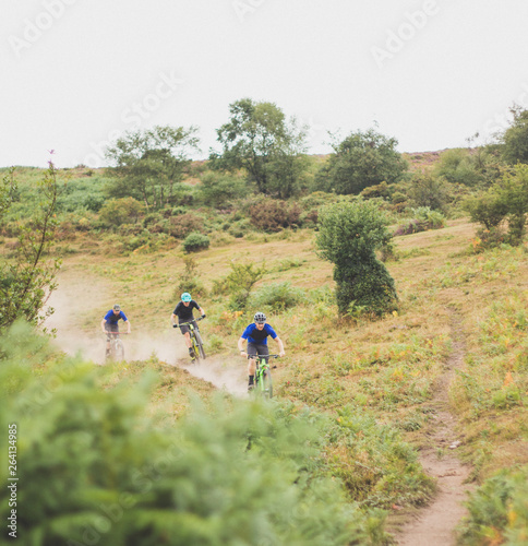 Friends enjoy mountain biking dusty trail together