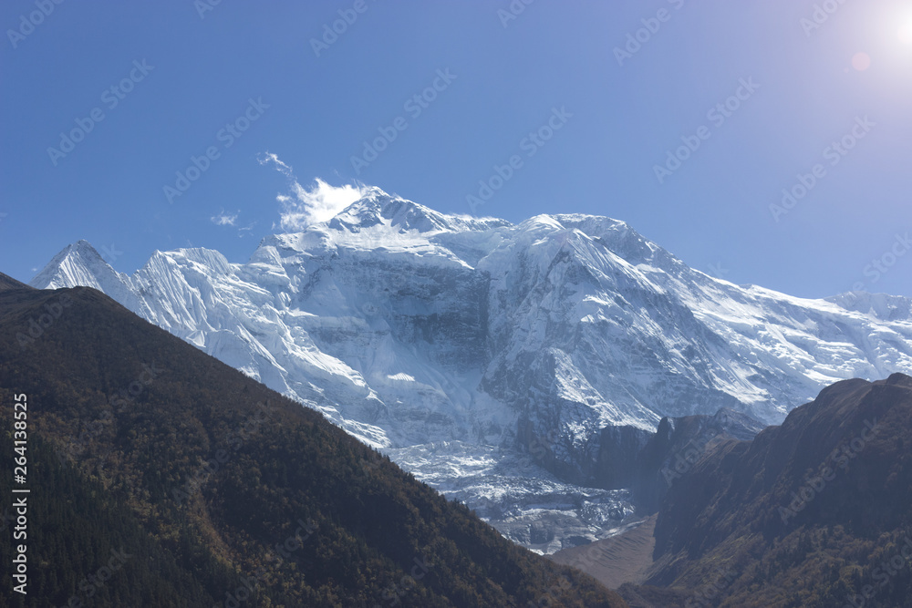 colossal snowy peaks peeking out from behind the hills covered with trees. annapurna travel