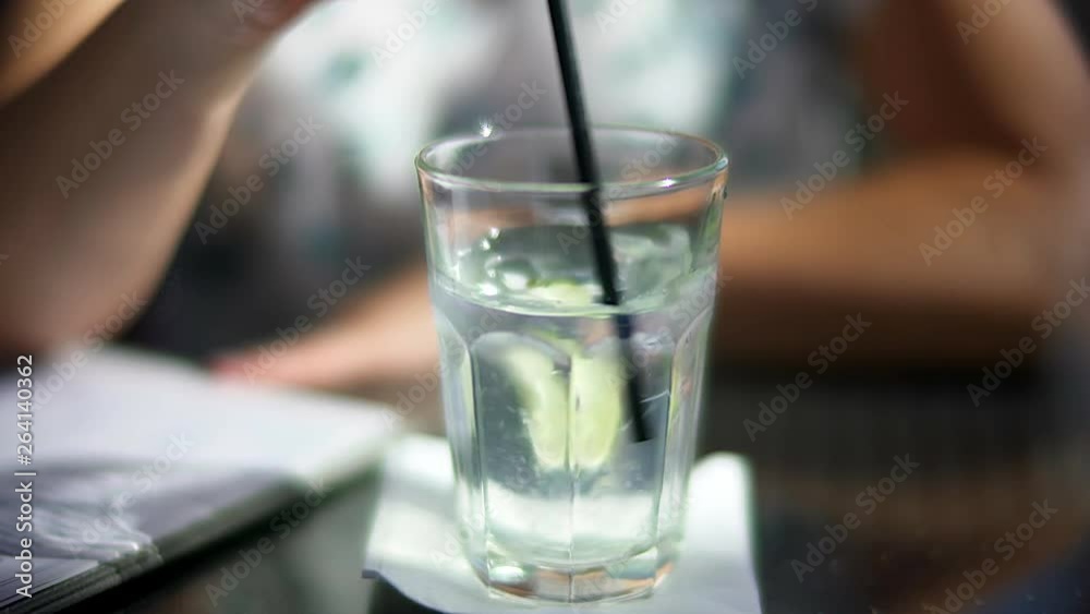 Woman Stirring Cocktail with Lemon and Ice with Straw