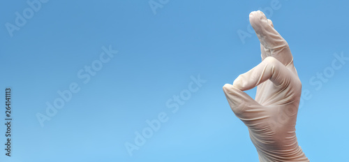 Banner.A fragment of a hand in medical latex white gloves that shows an OK gesture on a blue background. Medical background. Hand ok sign on blue background. Fingers showing Okay symbol.