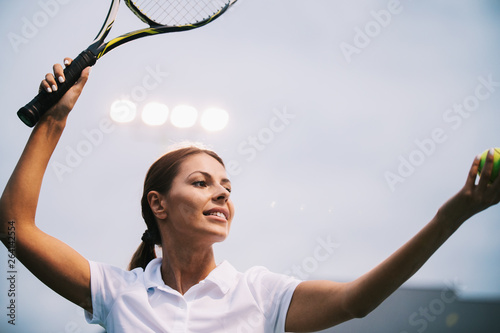 Woman tennis player smiling while holding the racket during tennis match