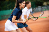 Young happy women friends playing tennis at tennis court