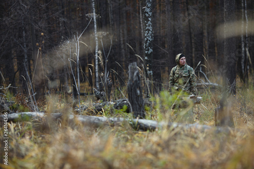 Man traveler in camouflage clothes in the autumn forest. Extreme travel. Survival in the wild.