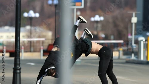 Two young men performing acrobatic parkour tricks and somersault in the end photo