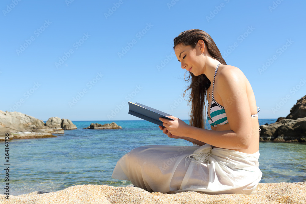 Woman reading a book on summer vacation on the beach