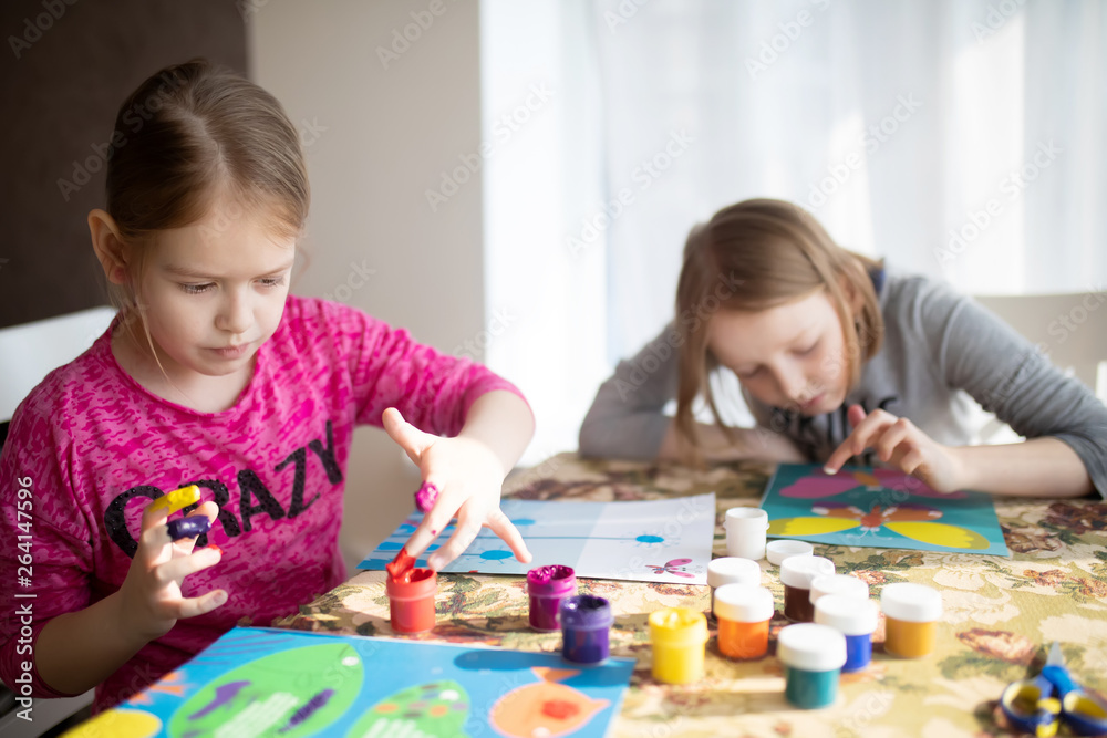 Fototapeta premium Two sisters little girls drawing with fingers on paper. Play, fun, childhood. Montessori school