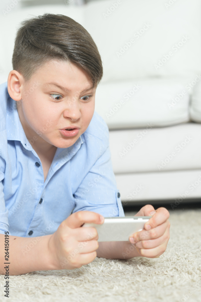 Portrait of young boy with smartphone playing the game at home Portrait of young boy with smartphone playing the game at home