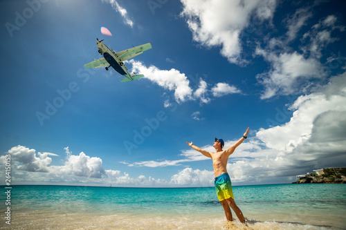 Man with airplane flying over on famous Maho beach