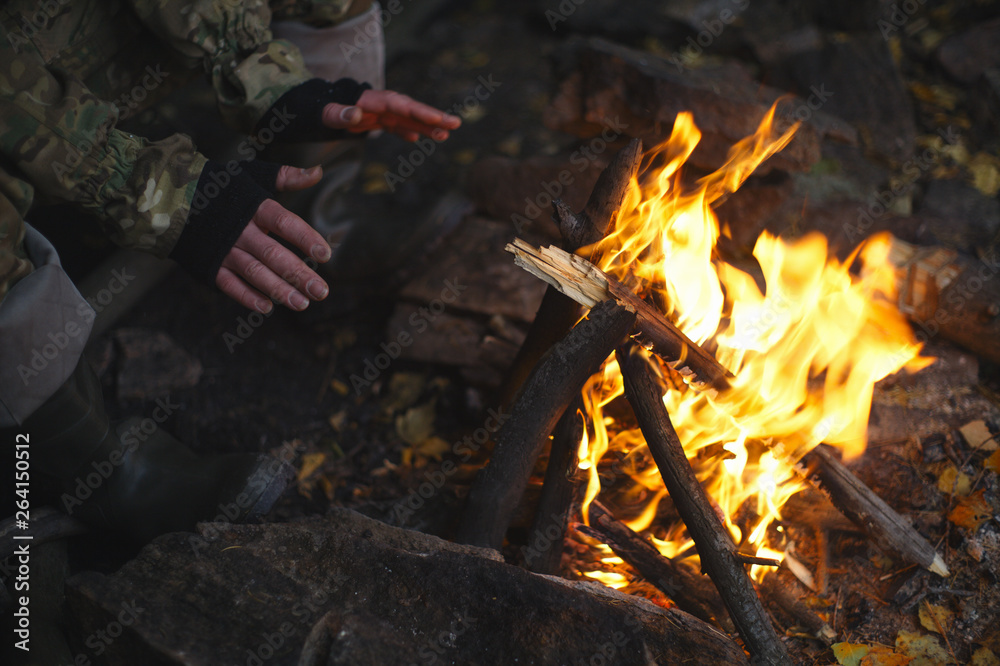 Man traveler warming his hands at a fire closeup. Extreme travel. Survival in the wild. Man traveler warming his hands at a fire closeup. Extreme travel. Survival in the wild.