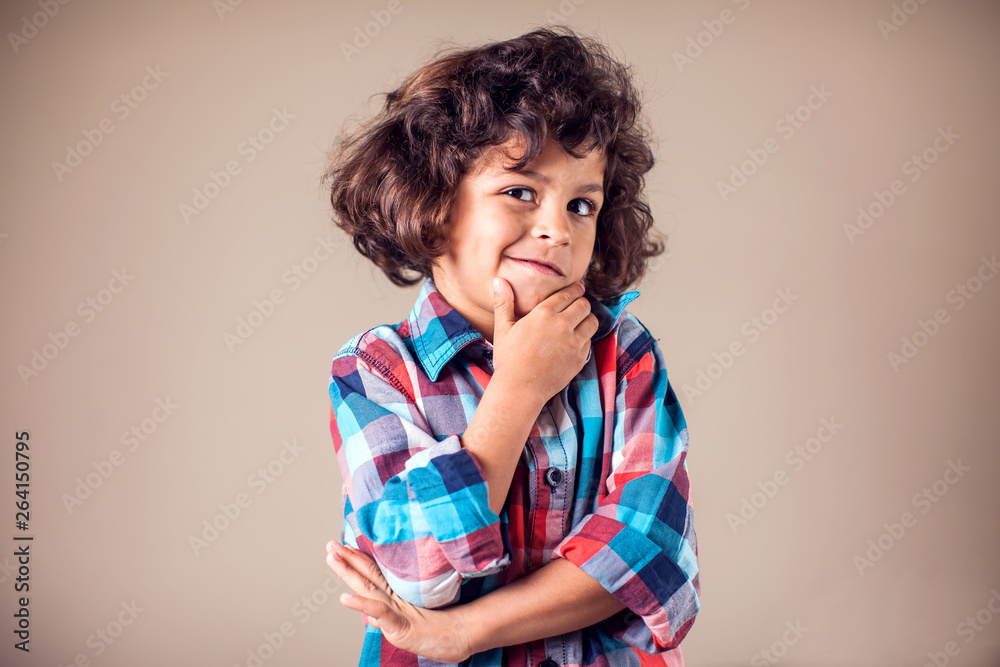 Young boy is daydreaming over grey background. Choldren, emotions concept
