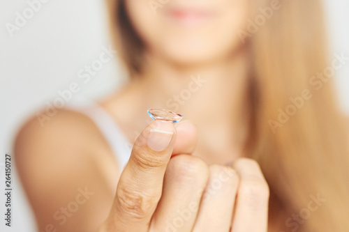 Young woman holding contact lens. Eyewear  eyesight and vision  eye care and health  ophthalmology and optometry concept  selective focus on finger