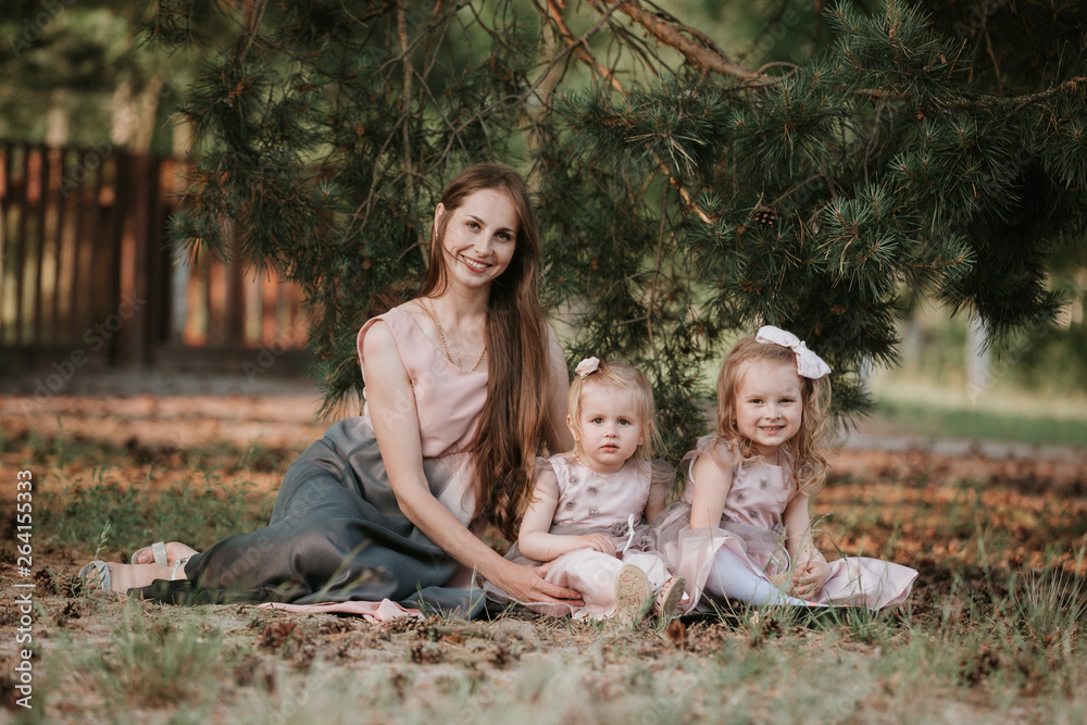 a wonderful portrait of mom with two daughters in the park. Mother and two daughters whirling. Mother holds daughters on hands. Family time together. a wonderful portrait of mom with two daughters in the park. Mother and two daughters whirling. Mother holds daughters on hands. Family time together.