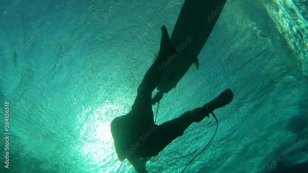 Underwater view of the surfer floating on the surface with surfboard ...