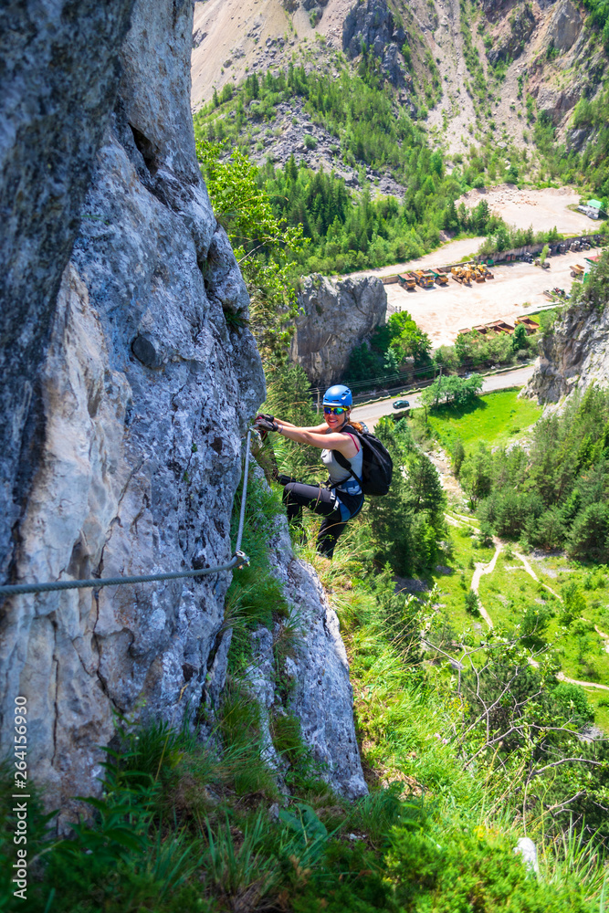 Obraz premium Female climber hanging from a via ferrata cable on
