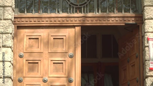 Old wooden door on in the course of the building. Opens and closes against a stone wall. Shot in motion