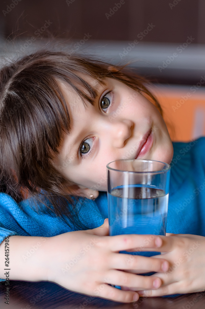 Adorable smiling little girl drinking water in kitchen. Health and beauty concept Adorable smiling little girl drinking water in kitchen. Health and beauty concept