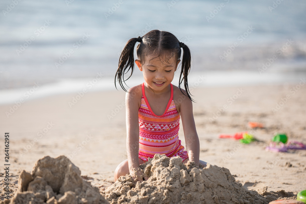 Happy little girl playing with sand on beach Stock Photo | Adobe Stock