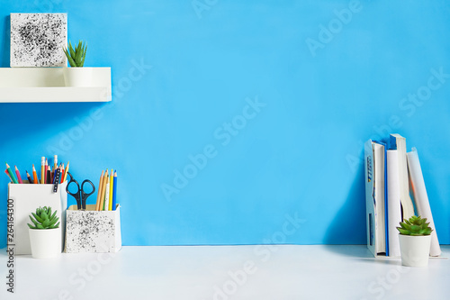 office creative desk with supplies, and blue wall.