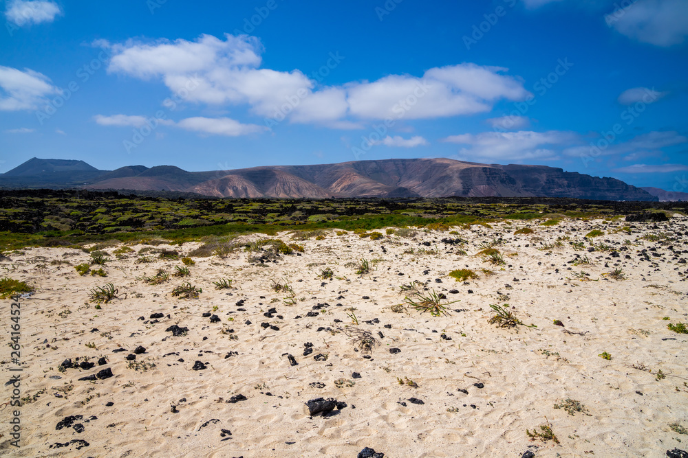Spain, Lanzarote, Impressive volcanic countryside of mountains, green vegetation and white sand
