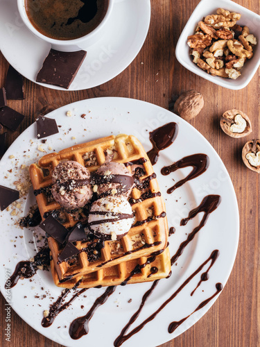 Belgian waffles with ice cream. Chocolate and nuts. wooden table. Rustik