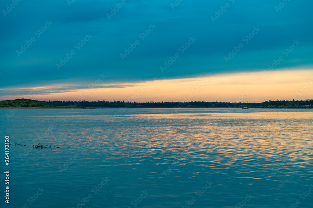Fototapeta premium summer landscape on the banks of the green river at sunset, Russia