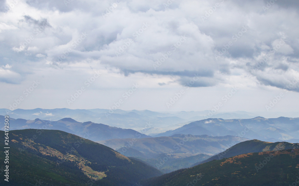 Mountain landscape with green grass against the sky. Panoramic view of the cliffs without people. Wildlife on hills and elevation with clouds.