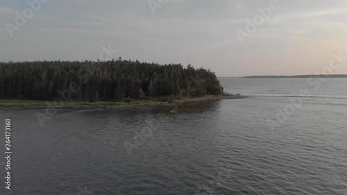 Cinematic drone / aerial footage rotating showing someone canoeing in the coast of Kingsburg, Nova Scotia, Canada during summer season - sunset time. photo