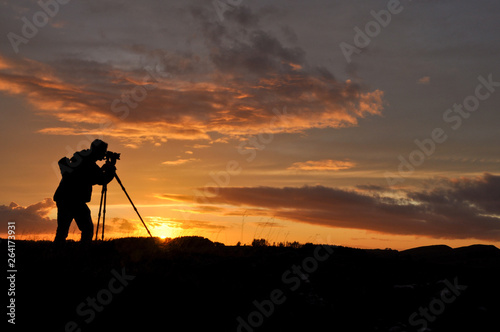 Silhouette of photographer with tripod against setting sun