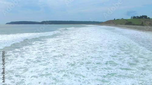 Cinematic drone / aerial footage rotating showing sea waves reaching the beach and a surfer in the water in Kingsburg, Nova Scotia, Canada during summer season. photo